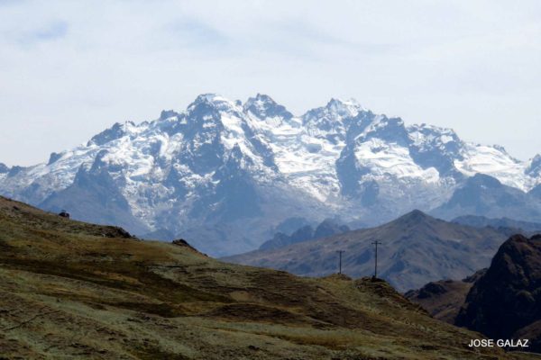 Looking over a grassy hillside at the snow-covered Andes mountains in the background