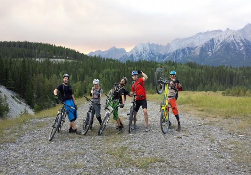 5 men posing with their bikes in the mountains