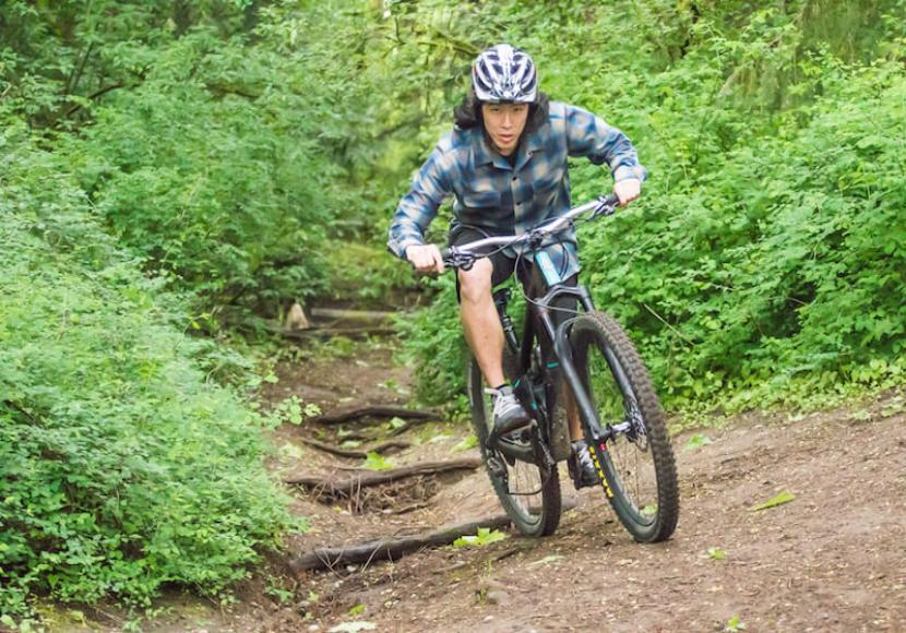 Mountain Biker looking directly at camera as comes down a trail through the woods