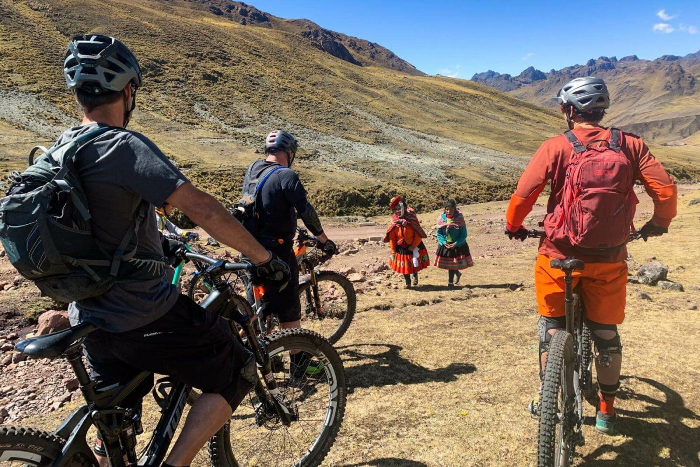 Riders on a mountain biking tour in Peru, stopping to say hello to locals