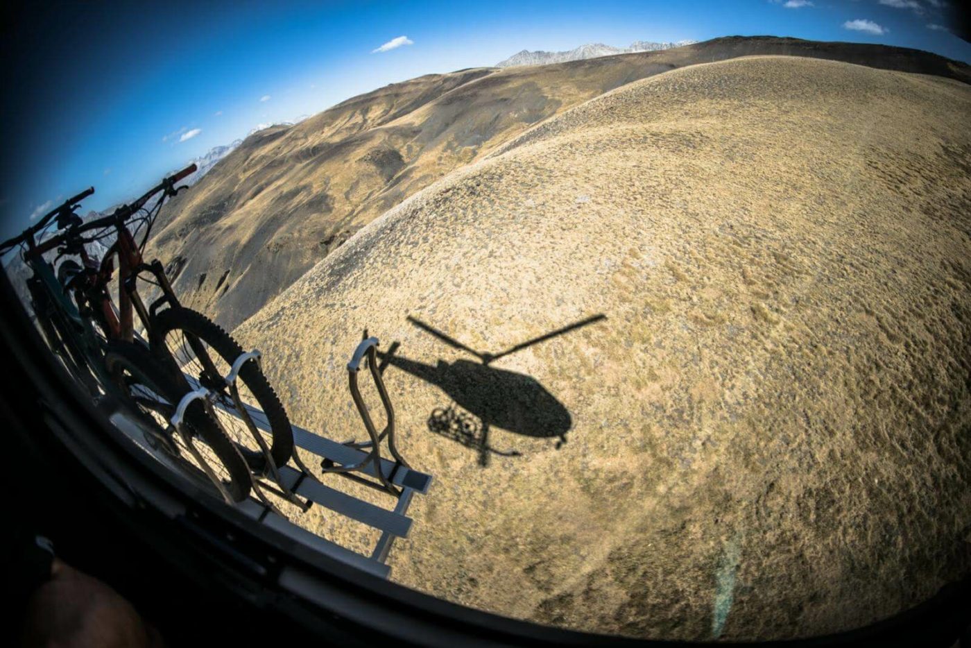 View from above, in the helicopter, of the helicopter's shadow as it takes mountain bike riders to Pyrenees mountains.