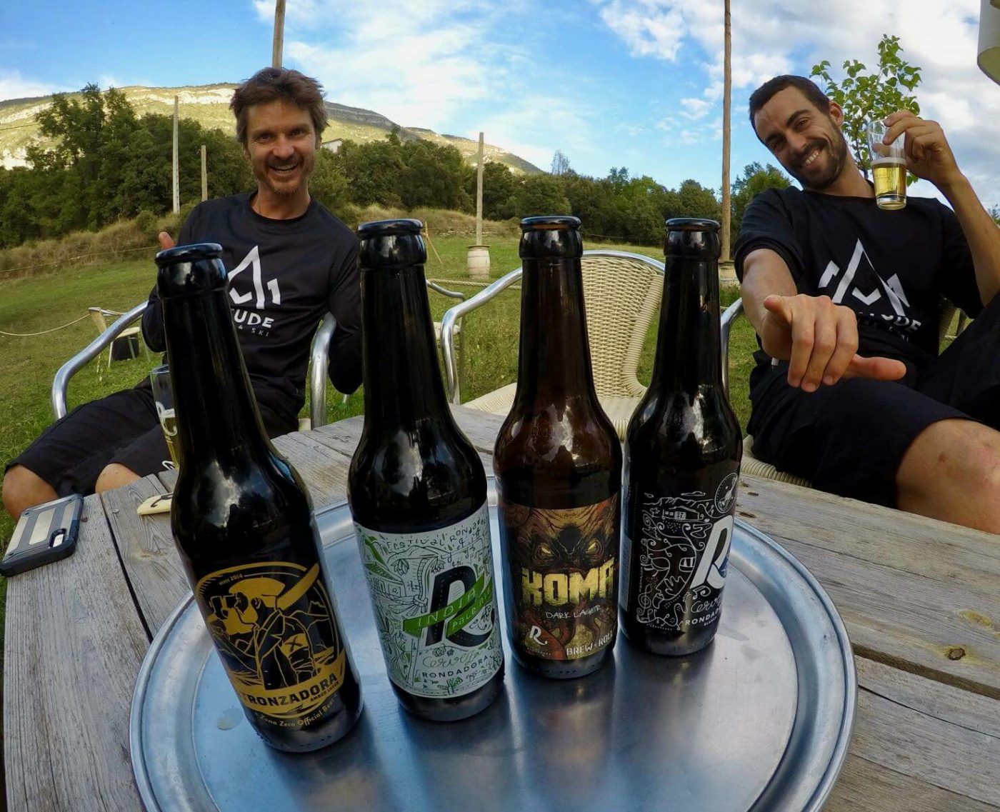 Two smiling mountain bike riders from the tour relaxing with beer.