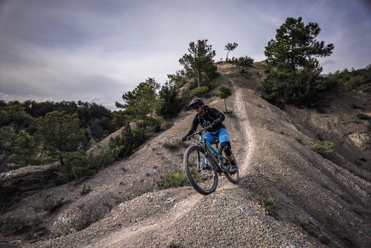 Mountain biker riding down a dirt hill on a trail through the Pyrenees in Spain.
