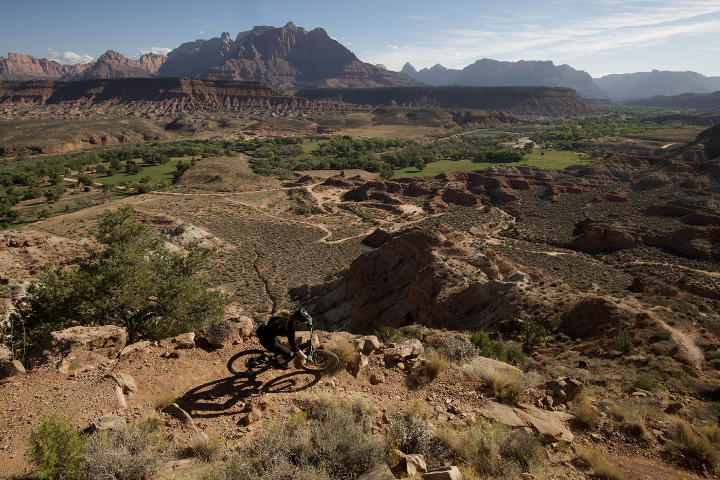 Overhead view of person riding a mountain bike on a red dirt trail surrounded by red sandstone cliffs