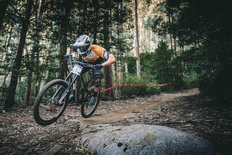Mountain Biker going fast over a rock and dirt trail in the woods