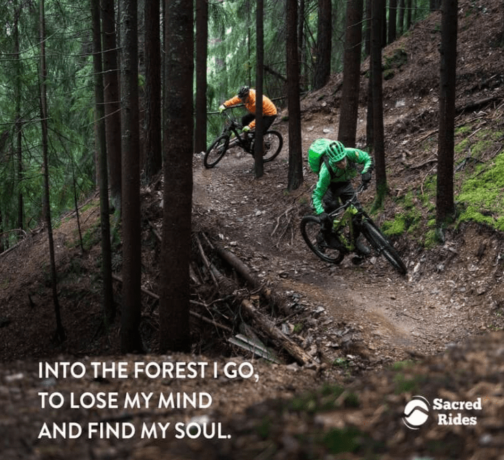 Two people riding mountain bikes quickly on trail through the woods with the caption, "Into the forest I go, to lose my mind and find my soul."