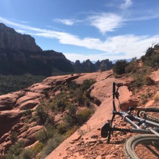 A mountain bike laying on a red desert trail to the right with more red desert rock all around